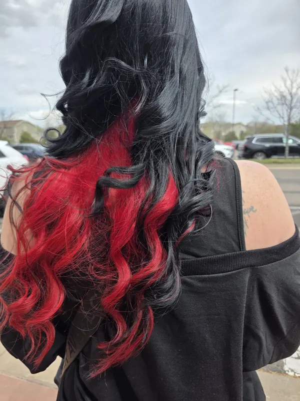 Black hair with vivid red underlights styled in waves