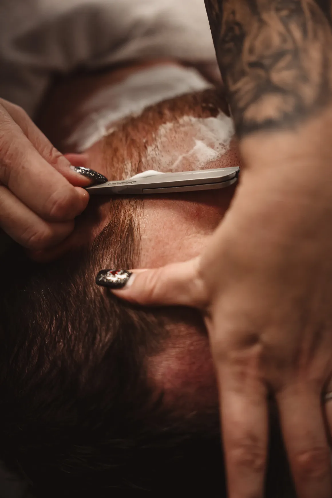 Close detail of a straight razor edging a beard line